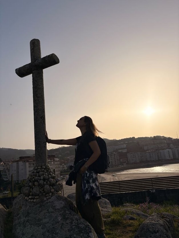 Alejandra Salcedo junto a una cruz al atardecer